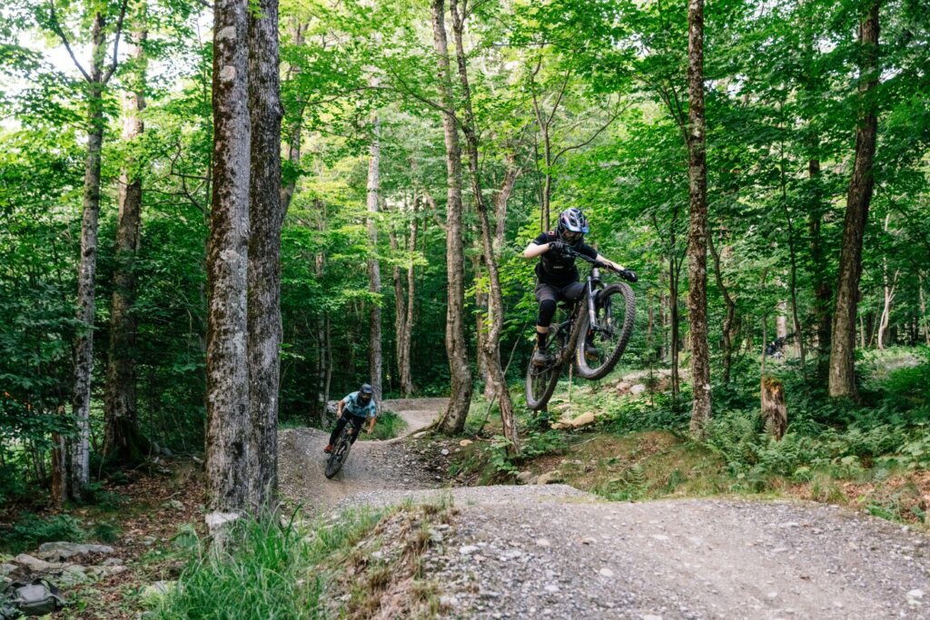 Two mountain bikers send a flow trail at the mountain bike park