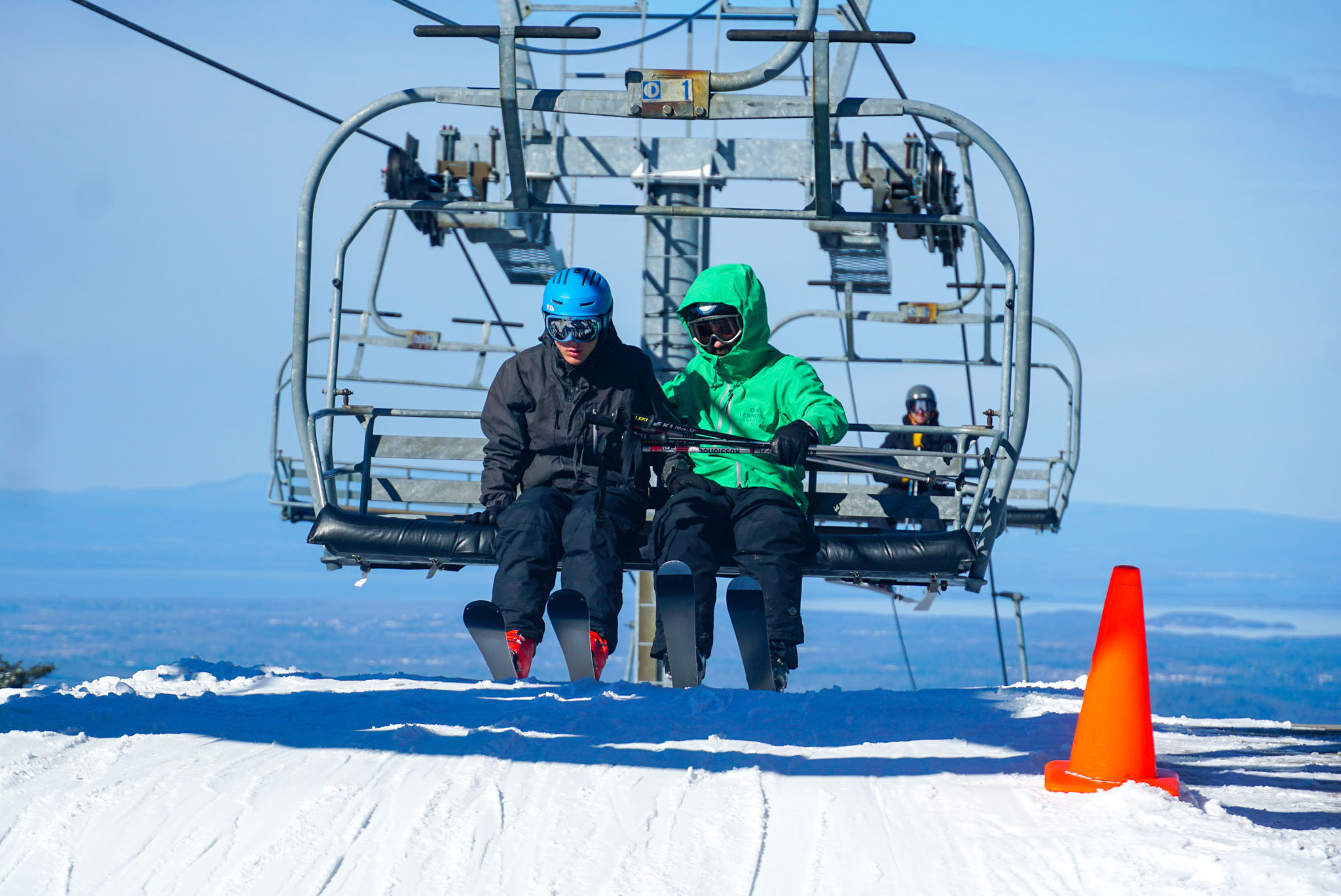 VT Adaptive volunteer and skier prepare to offload the ski lift with mountain views in the background