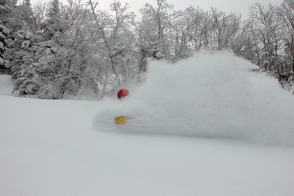 A person snowboarding in fresh powder at Bolton Valley